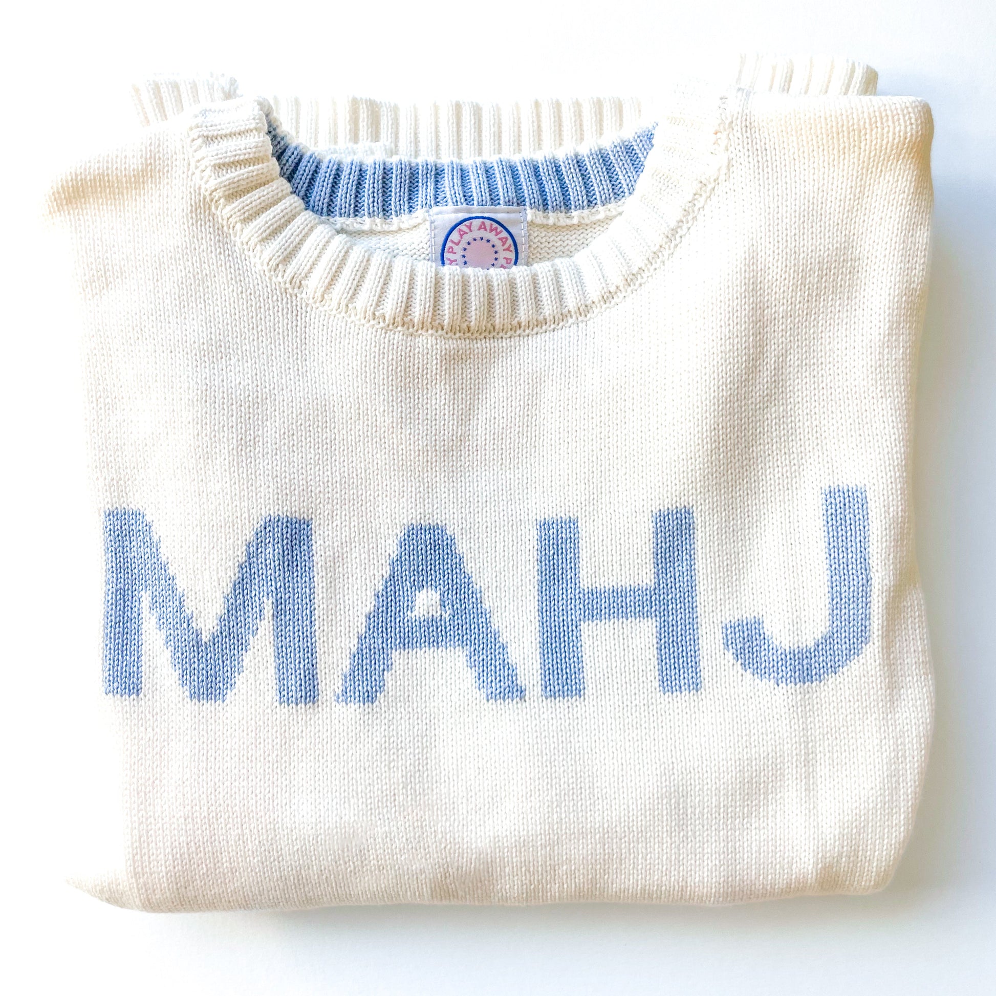 Folded white sweater with blue 'MAHJ' text on a white background