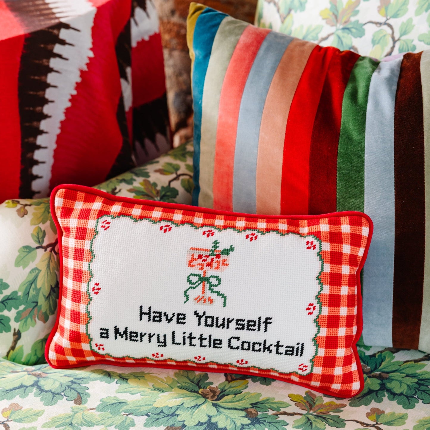 Decorative pillow with cross-stitched design and text on a colorful background