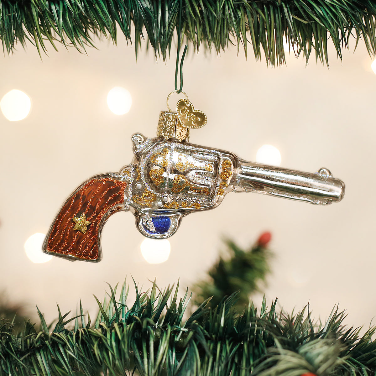 Decorative revolver ornament hanging on a Christmas tree.