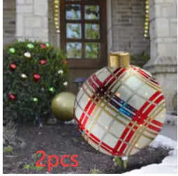 Decorative Christmas ornament with plaid pattern in front of a house with Christmas decorations.