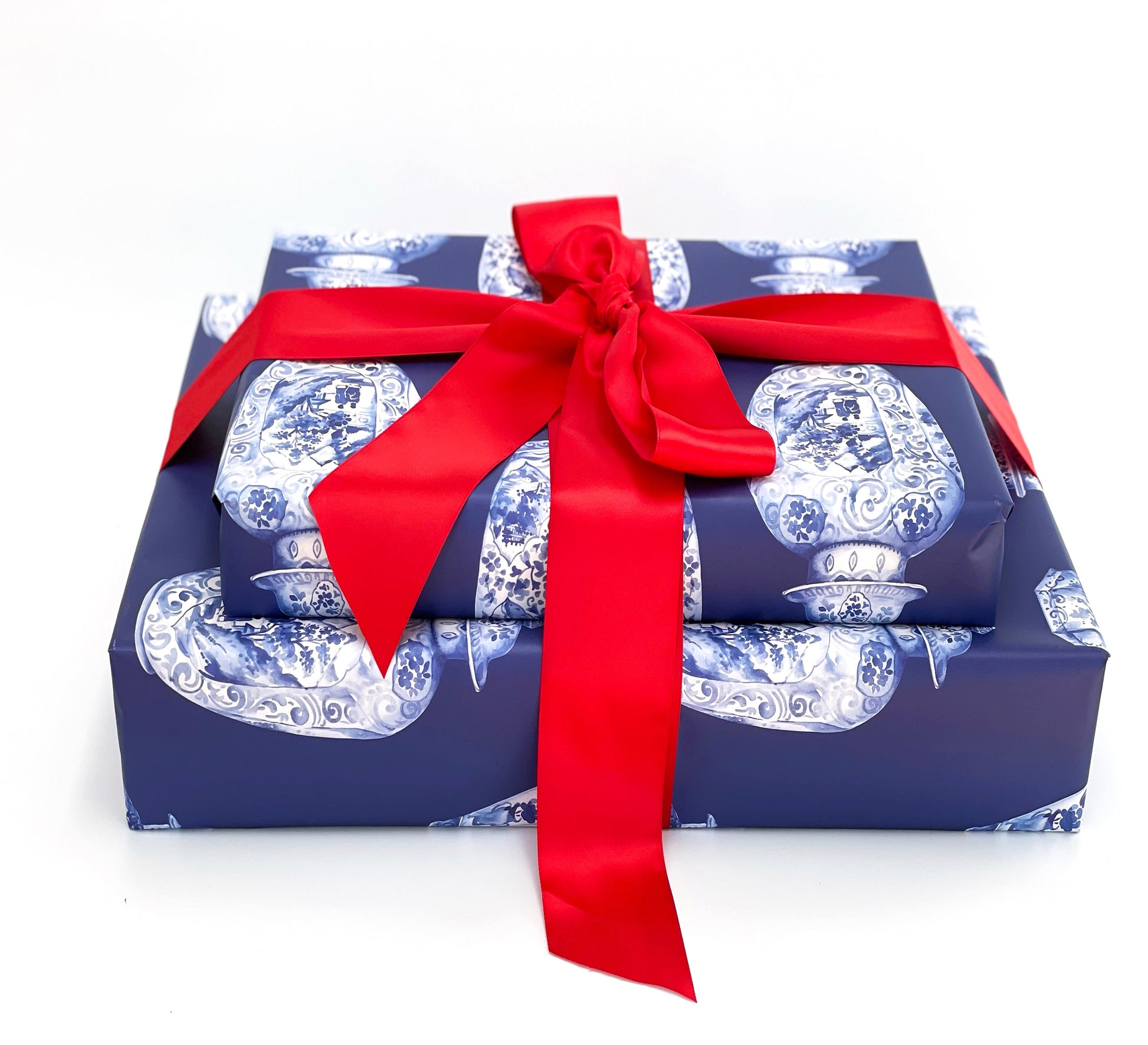 Two stacked gift boxes with blue and white pattern and a red ribbon on a white background