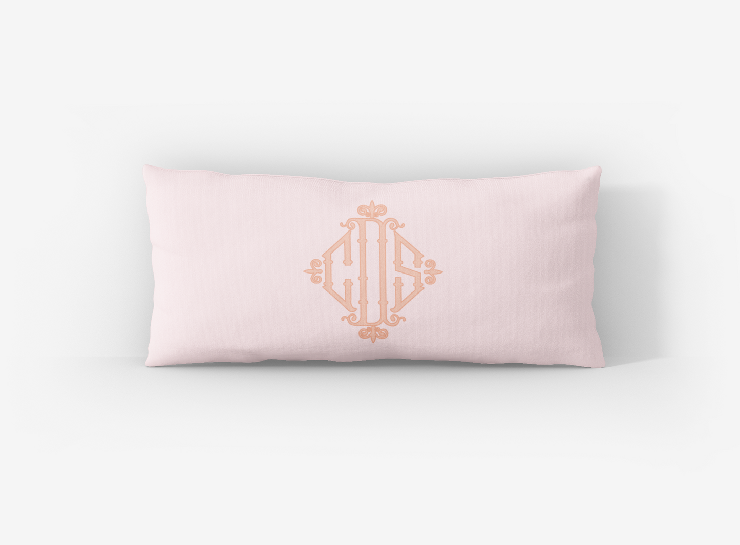 Pink pillow with gold monogram on a white background