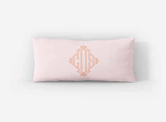 Pink pillow with gold monogram on a white background